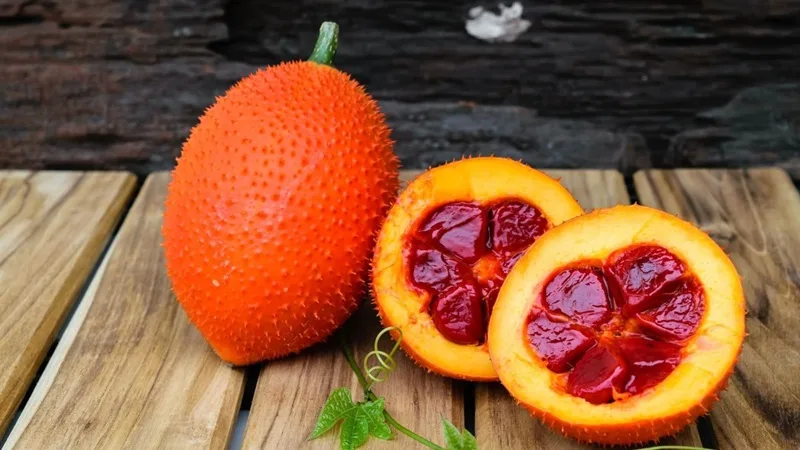 Cắt đôi quả gấc chín mọng để lộ phần hạt bọc màng đỏ rực rỡ.